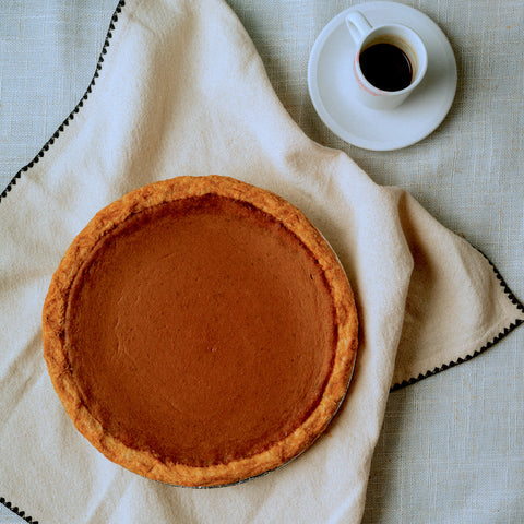 Pumpkin pie on a white cloth with a cup of coffee in the background