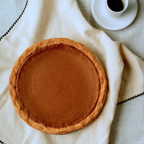 Pumpkin pie on light colored table cloth with cup of coffee