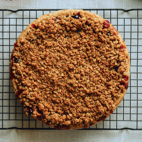 Round baked dessert with crumbly topping on a cooling rack