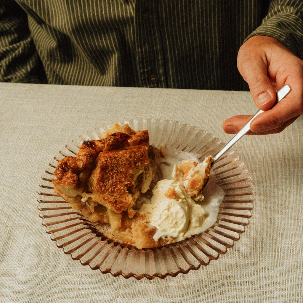 Apple pie with vanilla ice cream on a textured tablecloth