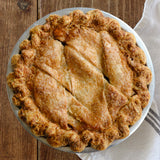 A golden-brown peach pie with crimped edges and decorative scored lines on top. 