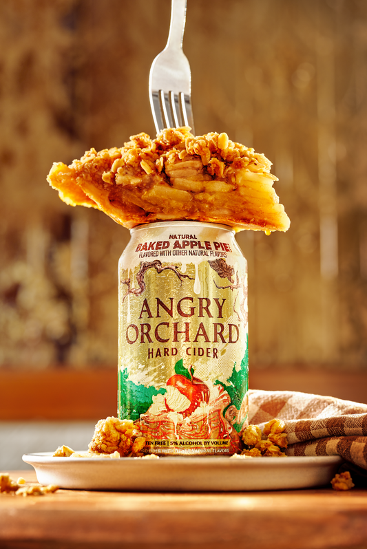 Slice of Boozy Baked Apple Pie sitting on top of a can of Angry Orchard Baked Apple Pie Hard Cider